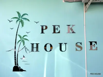 a wall with a palm tree and the words people inclusive at Pek House in Phuket Town