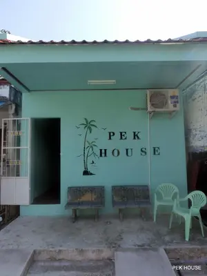 a pink house with two benches in front of it at Pek House in Phuket Town