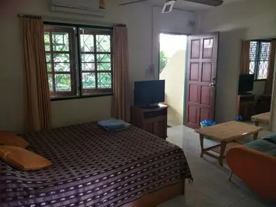 a bedroom with a bed and a tv and a door at Phuket Green Home in Karon Beach