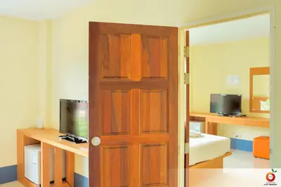 a wooden door in a room with a bed and a television at The Orange City Resort in Ao Nang Beach