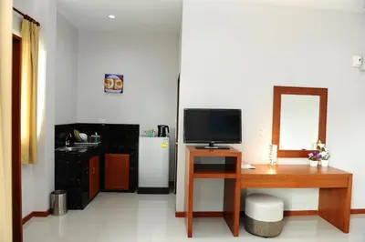 a room with a desk with a television and a refrigerator at Maikhao Beach Residence in Mai Khao Beach