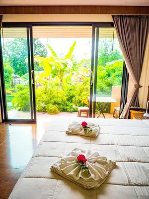 a bedroom with two beds and a large window at Baansuan Amaleena in Ko Yao Noi