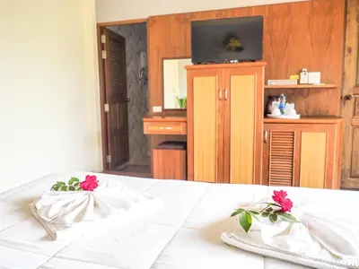 a bed with white sheets and red flowers on it at Baansuan Amaleena in Ko Yao Noi