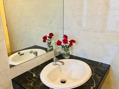 a bathroom with two sinks and red flowers in a mirror at Baansuan Amaleena in Ko Yao Noi
