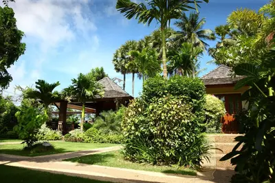 a house with palm trees in front of it at Pai Tan Villas - SHA Extra Plus in Bang Tao Beach