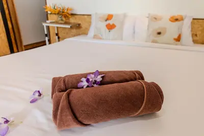 a brown towel on a bed with purple flowers at Sunrise House in Ko Yao Noi