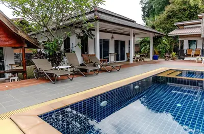 a swimming pool with chairs and a house at Sunrise House in Ko Yao Noi
