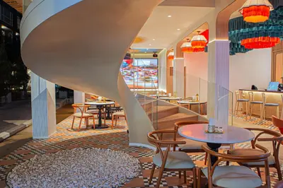 a restaurant with tables and chairs and a spiral staircase at The Lantern Resorts Patong in Patong Beach