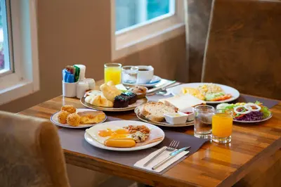 a table with plates of breakfast foods and orange juice at Thanthip Beach Resort Patong in Patong Beach
