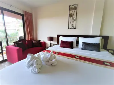 a bedroom with a large white bed and a red couch at Seven Seas Hotel Patong Beach in Patong Beach