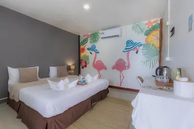 two beds in a room with flamingos on the wall at Phi Phi Cozy Seafront Resort in Phi Phi Don