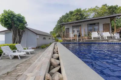 a swimming pool with white chairs and a house at Phi Phi Cozy Seafront Resort in Phi Phi Don