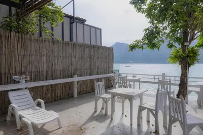 a group of white chairs and tables on a patio overlooking the water at Phi Phi Cozy Seafront Resort in Phi Phi Don