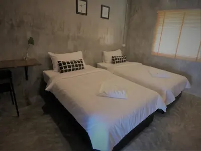 two twin beds in a room with a table and window at The Simple Koh Yao Noi in Ko Yao Noi