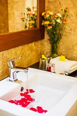 a bathroom sink with red flowers on a counter at Airport Resort Phuket in Nai Yang Beach