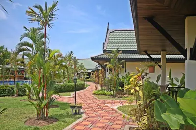 a walkway in front of a house with palm trees at Airport Resort Phuket in Nai Yang Beach