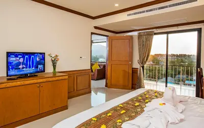 a bedroom with a bed and a tv and a balcony at Airport Resort Phuket in Nai Yang Beach