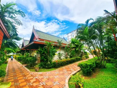 a person walking down a brick path in front of a building at Airport Resort Phuket in Nai Yang Beach