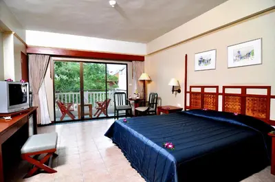 a bedroom with a blue bed and a balcony at Karon Princess Hotel SHA EXTRA Plus in Karon Beach