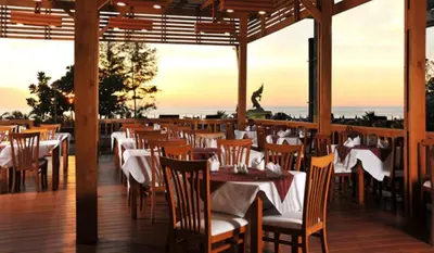 a restaurant with tables and chairs with the ocean in the background at Karon Princess Hotel SHA EXTRA Plus in Karon Beach