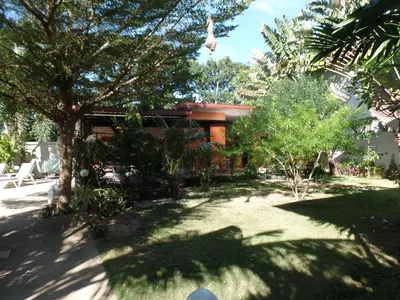 a house with a yard with trees in front of it at Babylon Pool Villas in Nai Harn Beach