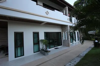a white house with windows and a courtyard at Babylon Pool Villas in Nai Harn Beach