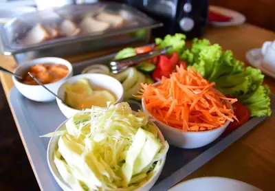 a tray with bowls of vegetables on a table at Anissa Resort Koh Yao Yai in Ko Yao Yai