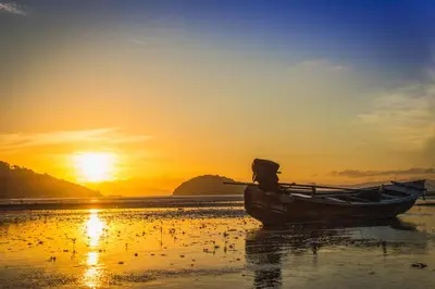 a boat sitting on the beach at sunset at Anissa Resort Koh Yao Yai in Ko Yao Yai