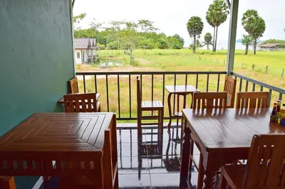 a balcony with tables and chairs and a view of a field at Anissa Resort Koh Yao Yai in Ko Yao Yai