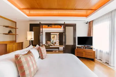 a hotel room with a bed and a television at Trisara Villas & Residences Phuket in Nai Thon Beach