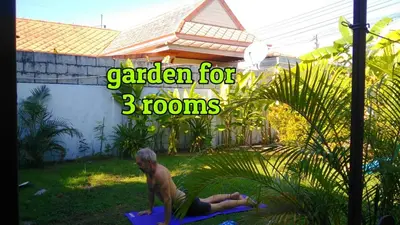 a man sitting on a mat in the yard at Studio with aircon n kitchen in Bang Tao Beach