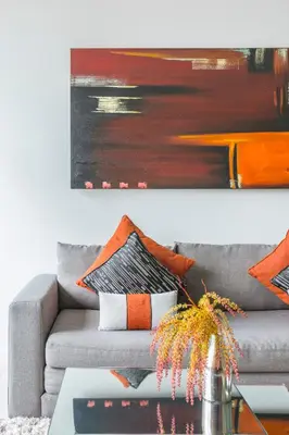a living room with a gray couch with orange pillows at Oceanstone by Holy Cow, 2-BR, 90 m2, pool view in Bang Tao Beach