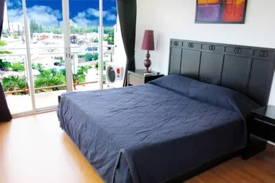 a bedroom with a blue bed and a large window at Orchid Kathu Heights Service Apartments in Kathu