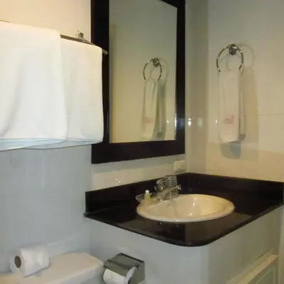 a bathroom with a sink and a toilet and towels at Orchid Kathu Heights Service Apartments in Kathu