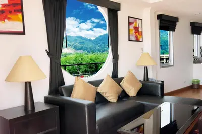 a living room with a couch and a large window at Orchid Kathu Heights Service Apartments in Kathu