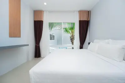 a bedroom with a large white bed and a window at The One Cozy, Phuket in Chalong