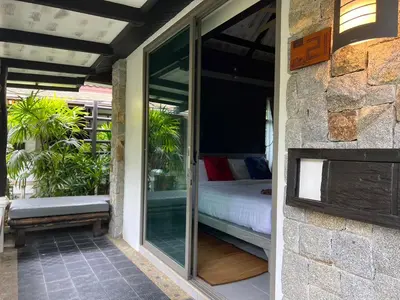 a glass door leading to a bedroom with a bed at Bangtao Beach Chalet Resort in Bang Tao Beach