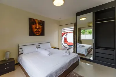 a bedroom with a large bed and a mirror at Villa With Pool in Bang Tao Beach