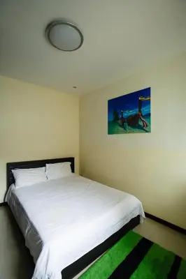 a bedroom with a white bed with a green rug at Villa With Pool in Bang Tao Beach