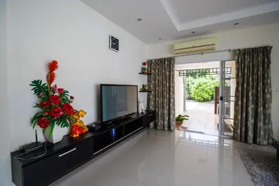 a living room with a flat screen tv and flowers at Villa With Pool in Bang Tao Beach