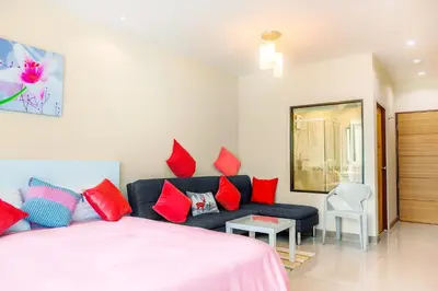 a bedroom with a bed and a couch with red pillows at The Nai Thon Condominium Unit in Nai Thon Beach