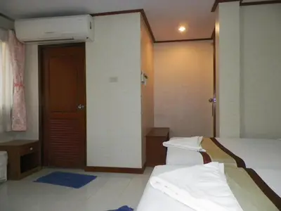 a hotel room with two beds and a door at Natacha Hotel in Phi Phi Don