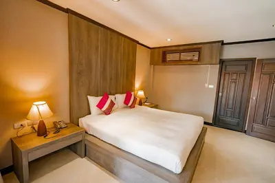 a bedroom with a bed and a table with a lamp at Naiya Buree Boutique Resort Nai Harn Beach in Rawai Beach