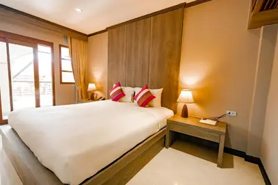a bedroom with a large white bed and a table at Naiya Buree Boutique Resort Nai Harn Beach in Rawai Beach