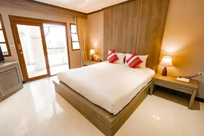 a bedroom with a large white bed with red pillows at Naiya Buree Boutique Resort Nai Harn Beach in Rawai Beach