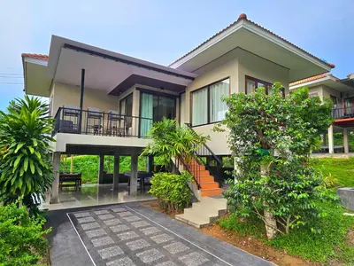 a house with a balcony and a yard at Krabi Green Hill Pool Villas in Ban Nong Thale