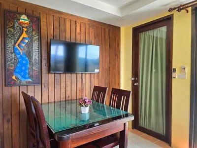 a dining room with a table and a television on a wall at Krabi Green Hill Pool Villas in Ban Nong Thale