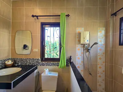 a bathroom with a toilet and a sink and a window at Krabi Green Hill Pool Villas in Ban Nong Thale