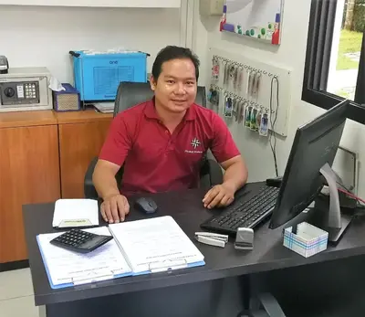 a man sitting at a desk with a computer at Phuket Riviera Villas Hotel in Nai Harn Beach