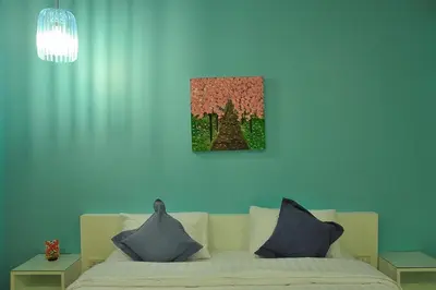 a bedroom with a white bed and a painting on the wall at Clear House Phuket in Kamala Beach